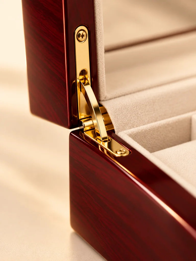 A macro of the exact Écrin Cinq open case focused on the polished gold hinge, front clasp edge, glos